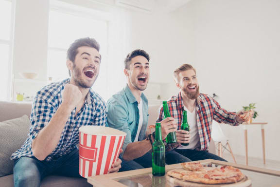 three men sitting on a couch eating popcorn and drinking beer at The Monroe Apartments, Austin, 78741