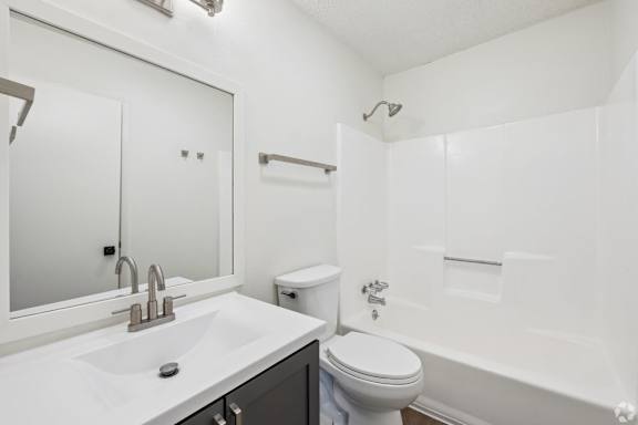 A white bathroom with a sink, toilet, and bathtub.
