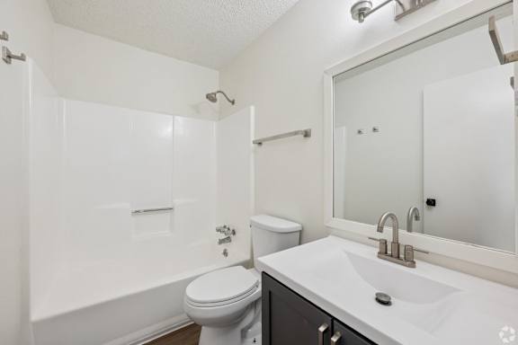 A white bathroom with a toilet, sink, and shower.