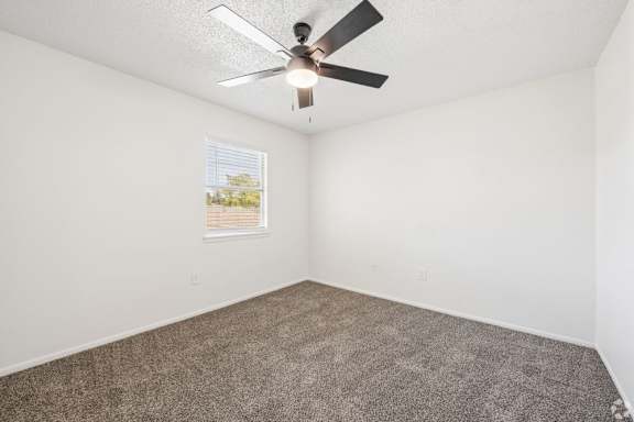 A room with a ceiling fan and carpeted floor.