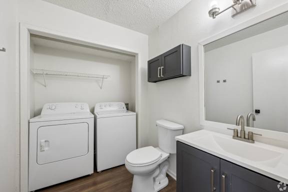 A small bathroom with a toilet, sink, and a washer and dryer.