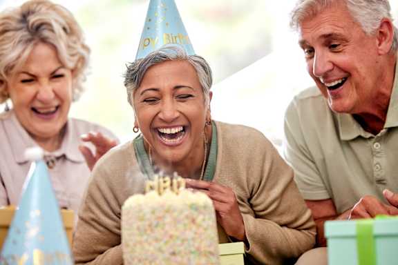 A group of people celebrating a birthday with a cake and party hats.