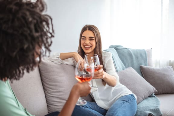 two women sitting on a couch drinking wine