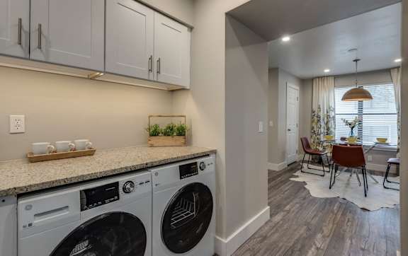 a washer and dryer in a laundry room with a table and chairs