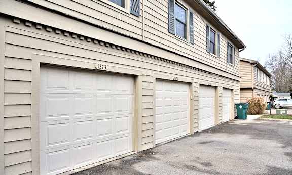 A two-car garage is attached to a tan house with the number 1373 on the front.