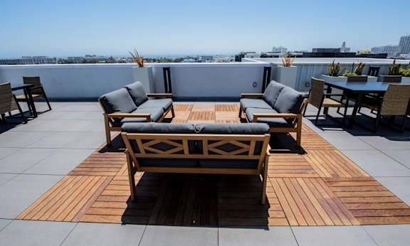 A wooden table and chairs are set up on a rooftop patio.