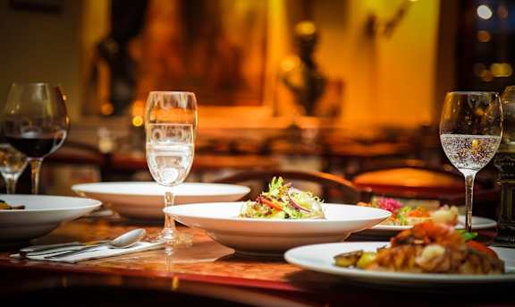 A table set for a meal with wine glasses and plates of food.