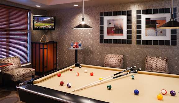 A pool table with a television and a chair in the background.