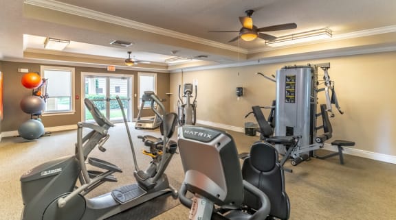 a room with a lot of exercise equipment and a ceiling fan