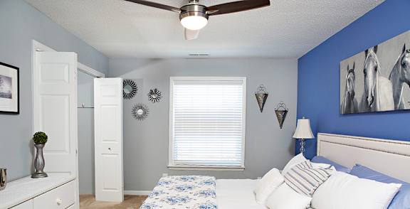 A bedroom with a bed, dresser, and ceiling fan.