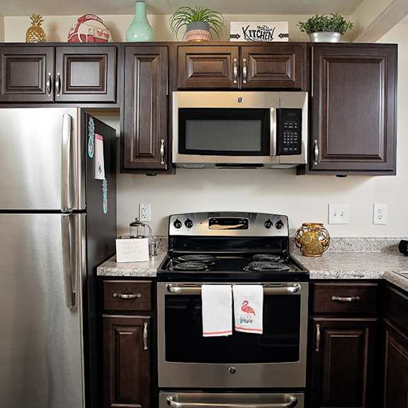A kitchen with a refrigerator, oven, microwave, and a sink.