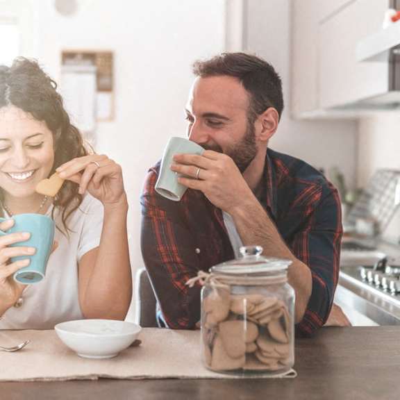 a man and a woman sitting at a kitchen table drinking coffee