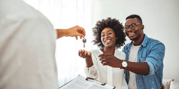 a group of people standing in a living room handing a car key to a man