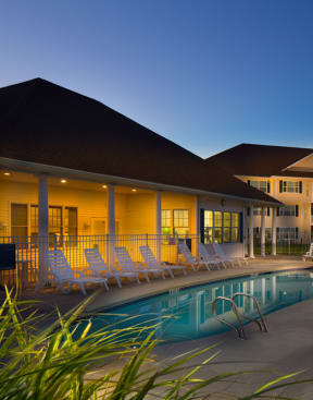 a swimming pool with chaise lounge chairs in front of an apartment building