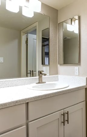 A bathroom with a sink, mirror, and toilet.