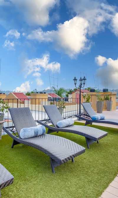 A patio with a wooden deck and grey cushioned lounge chairs.