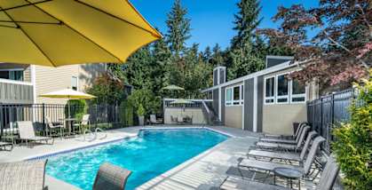 A pool surrounded by chairs and umbrellas.