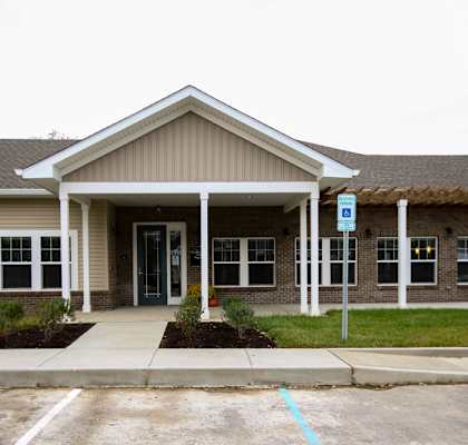 A building with a brown roof and a parking lot in front.