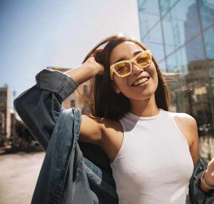 a woman holding a cell phone and wearing yellow sunglasses