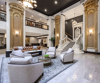 a living room with couches and chairs and a staircase