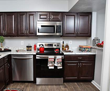 A kitchen with dark brown cabinets and a stainless steel dishwasher.