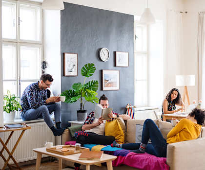 Four people are sitting on a couch in a living room.