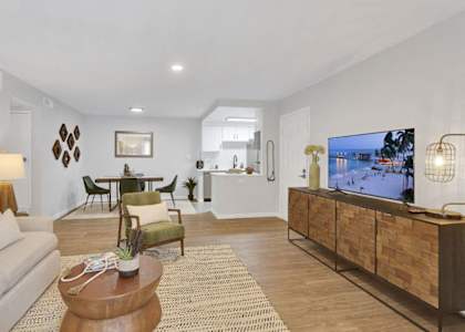 A living room with a white couch, a wooden coffee table, and a TV on a wooden cabinet.