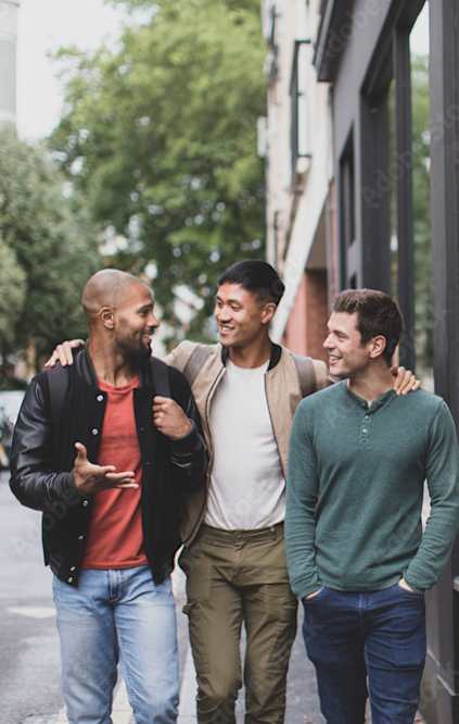 Three men are walking together on a city street.