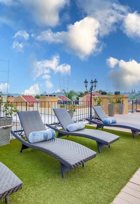 A patio with a wooden deck and grey cushioned lounge chairs.