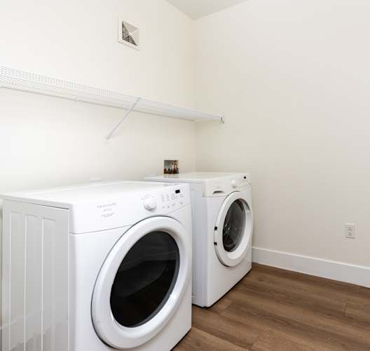 a washer and dryer in a laundry room with white walls and wooden floors at Miro at the Parc Apartments, Henderson , NV, 89074