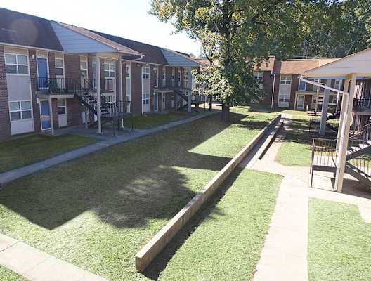 A sunny day at the apartment complex with green grass and trees.