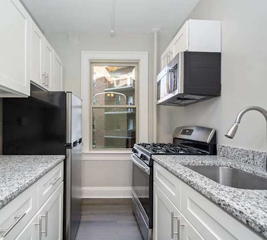 a kitchen with white cabinets and a window