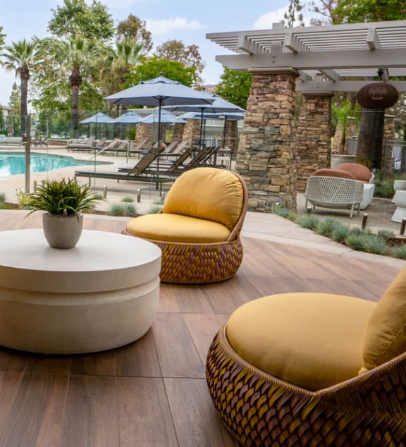 a lounge area with chairs and a table near a pool