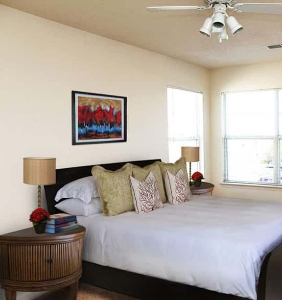 A bedroom with a bed, a chair, and a painting on the wall.