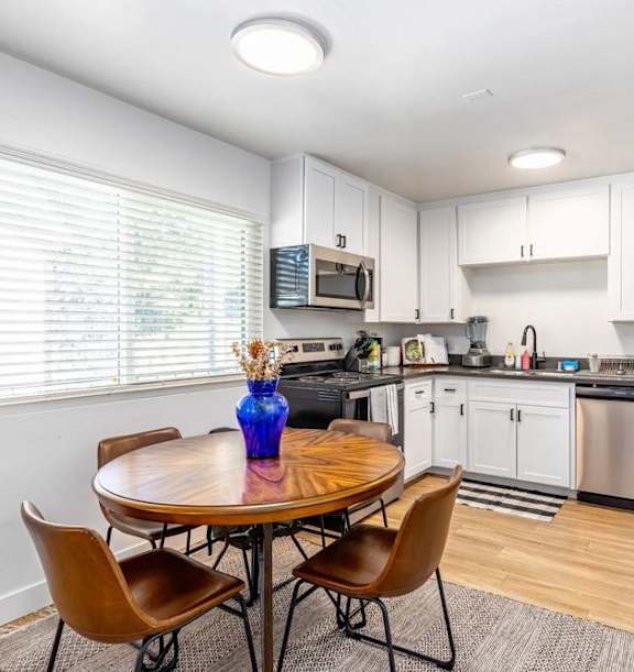 A kitchen with a table and chairs and a refrigerator.
