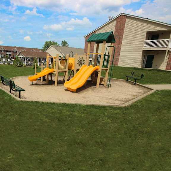 A playground with a yellow slide and green roofed structure.