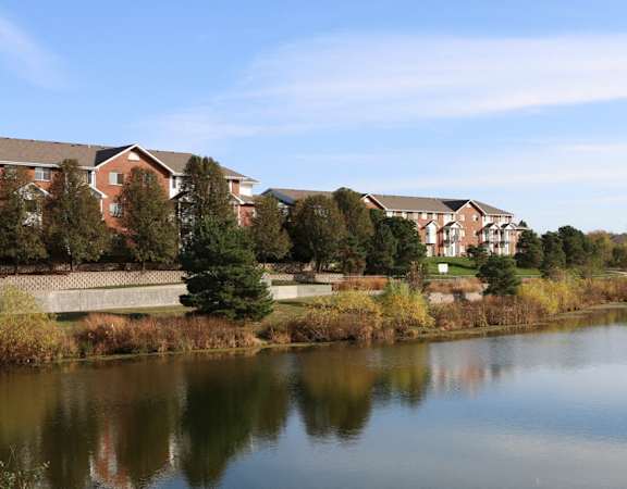 Tranquil lake view with apartments in the background.