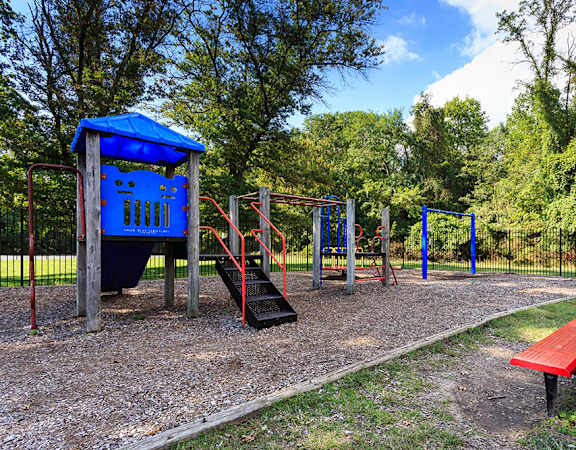 A playground with a blue shelter, red slide, and a red bench.