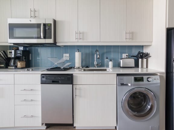 a kitchen with white cabinets and a silver washer and dryer