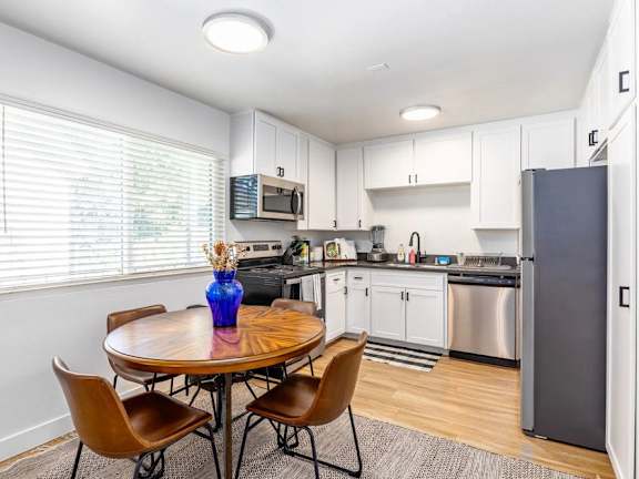 A kitchen with a table and chairs and a refrigerator.