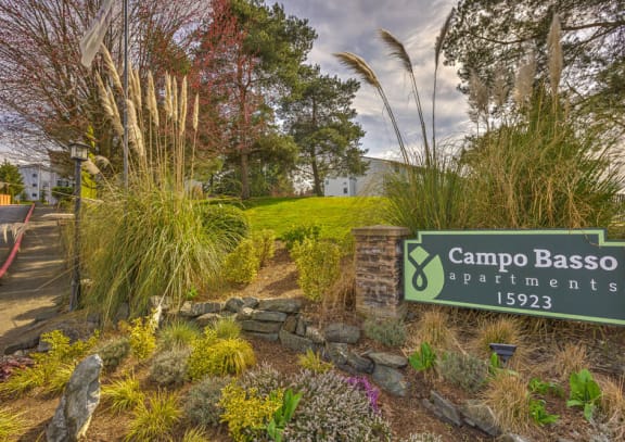 a garden with a sign that reads campo baso apartments at Campo Basso Apartment Homes in Lynnwood, WA