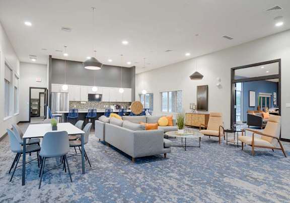 Resident clubhouse seating area with fireplace, blue accent wall, and contemporary furnishings near large windows.
