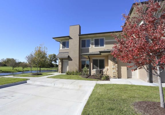 A house with a driveway and a tree with red leaves.