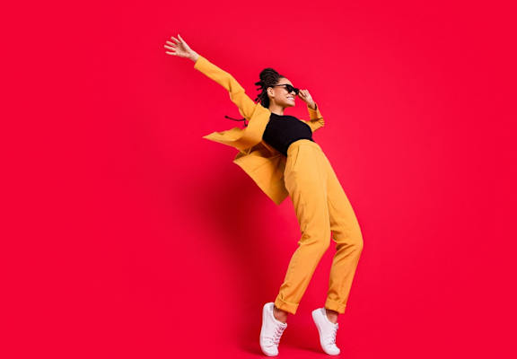 A person in a yellow outfit is captured mid-jump against a red background.