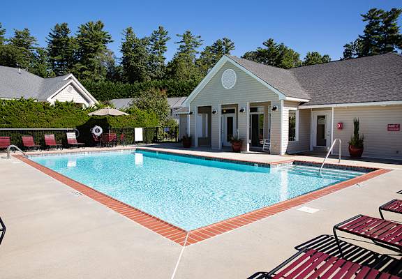A pool with red benches and a white building in the background.