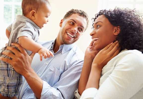 A family of three is sitting together, enjoying each other's company.