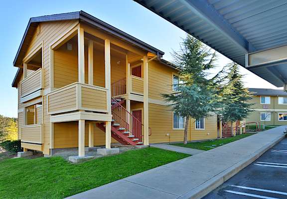 a yellow building with a porch and stairs on the side of it