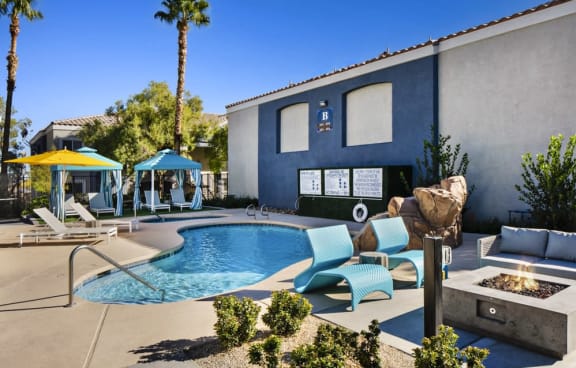 a swimming pool with a rock waterfall and lounge chairs at the retreat at thousand oaks apartments