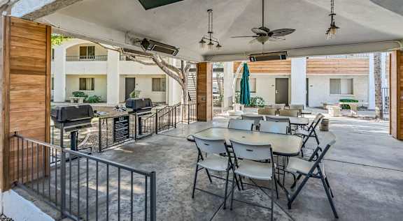 A patio with a table and chairs is covered by a roof. at Tides on East Cactus Apartments, Phoenix