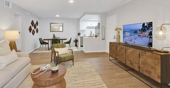 A living room with a white couch, a wooden coffee table, and a TV on a wooden cabinet.